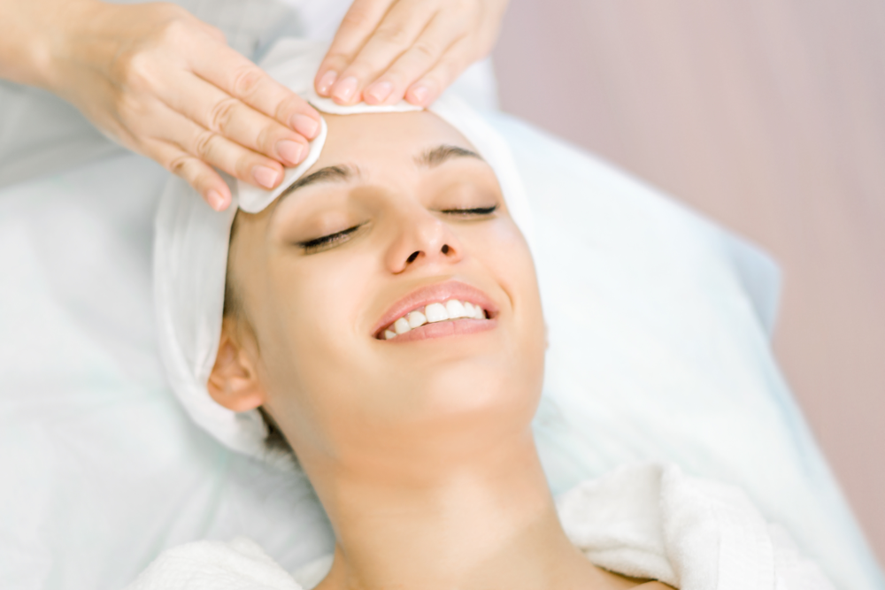Woman smiling during facial prep for acne scar treatment with chemical peels.